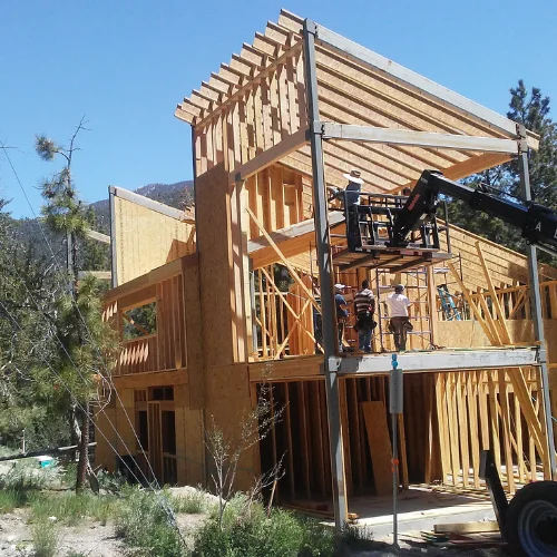 Wood-framed structure under construction with crews on a lift